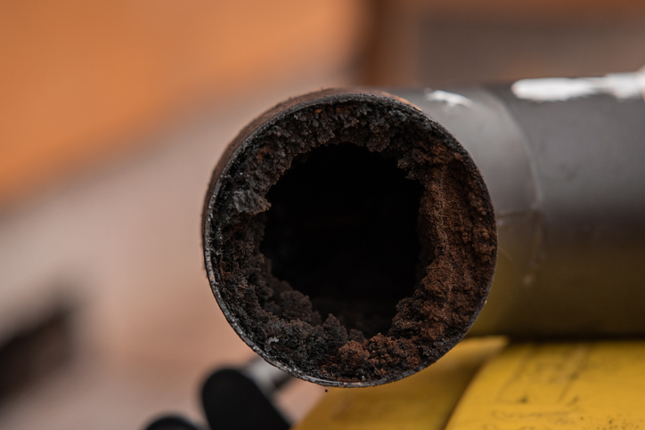 Image of the residue or thick layer of soot after a poor combustion in a fireplace, layered on the inner part of a chimney pipe or smokestack.