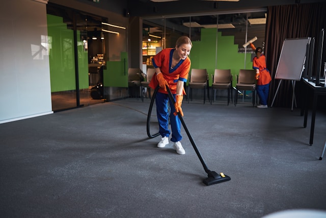 Image of a cleaner vacuuming the floor of an office building